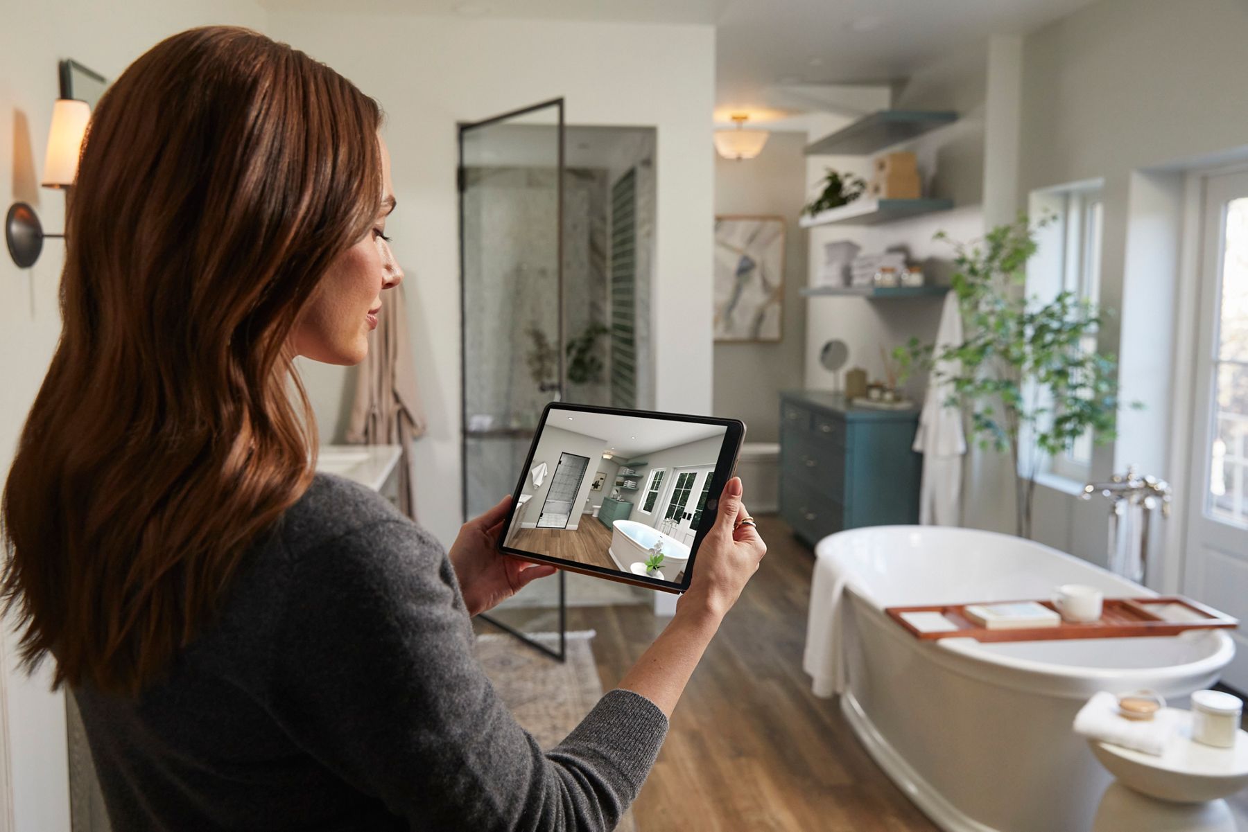 Two hands holding a tablet with a fully rendered, photorealstic bathroom floorplan on screen.
