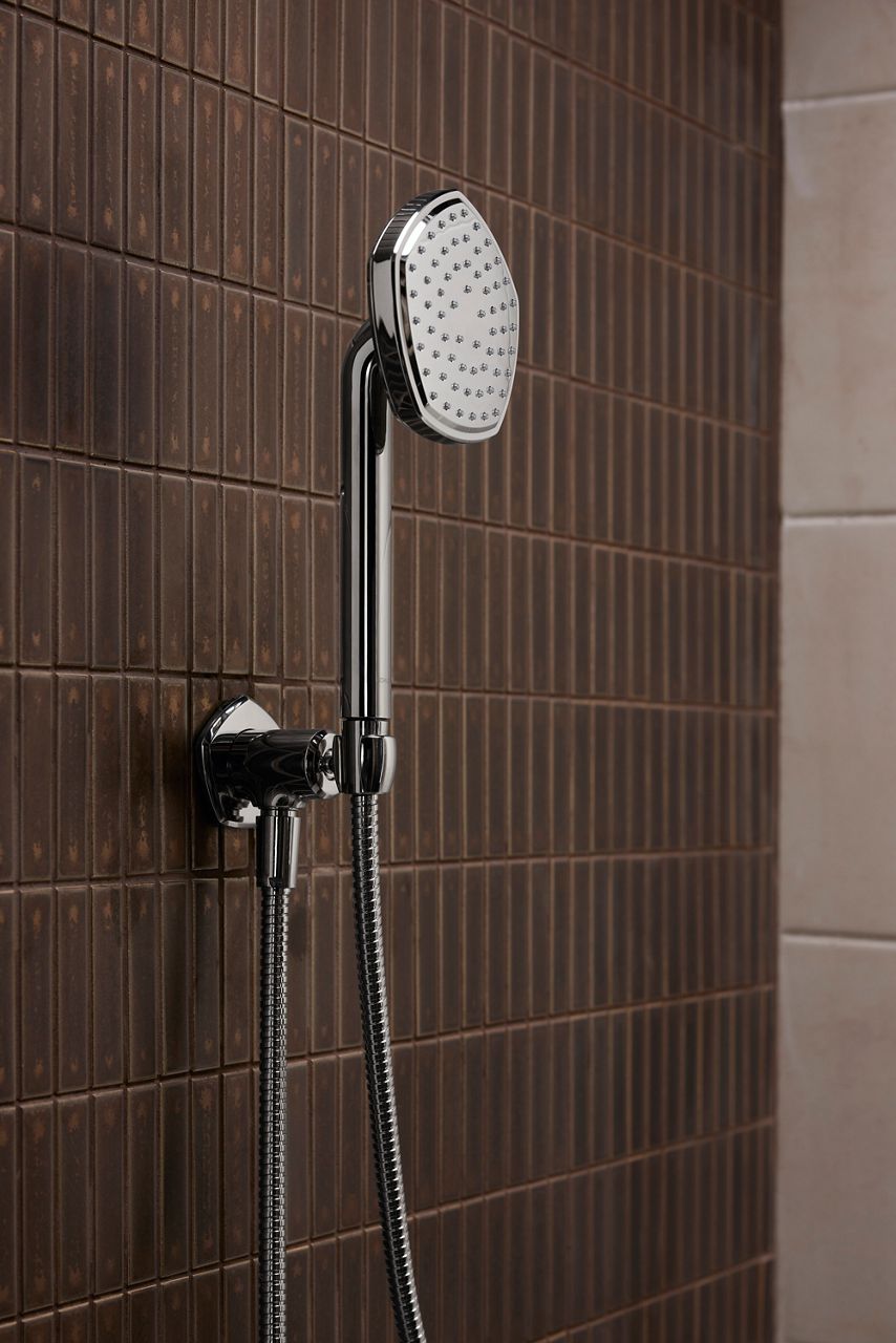 Chrome handshower mounted in tiled shower.