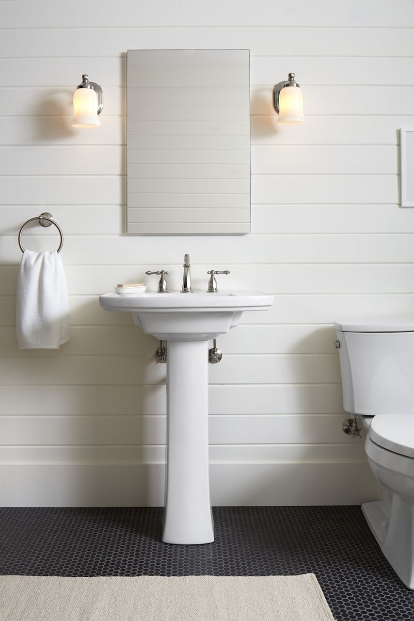 A KOHLER frameless medicine cabinet is flanked by two single-light sconces. A white pedestal sink is installed beneath the medicine cabinet.