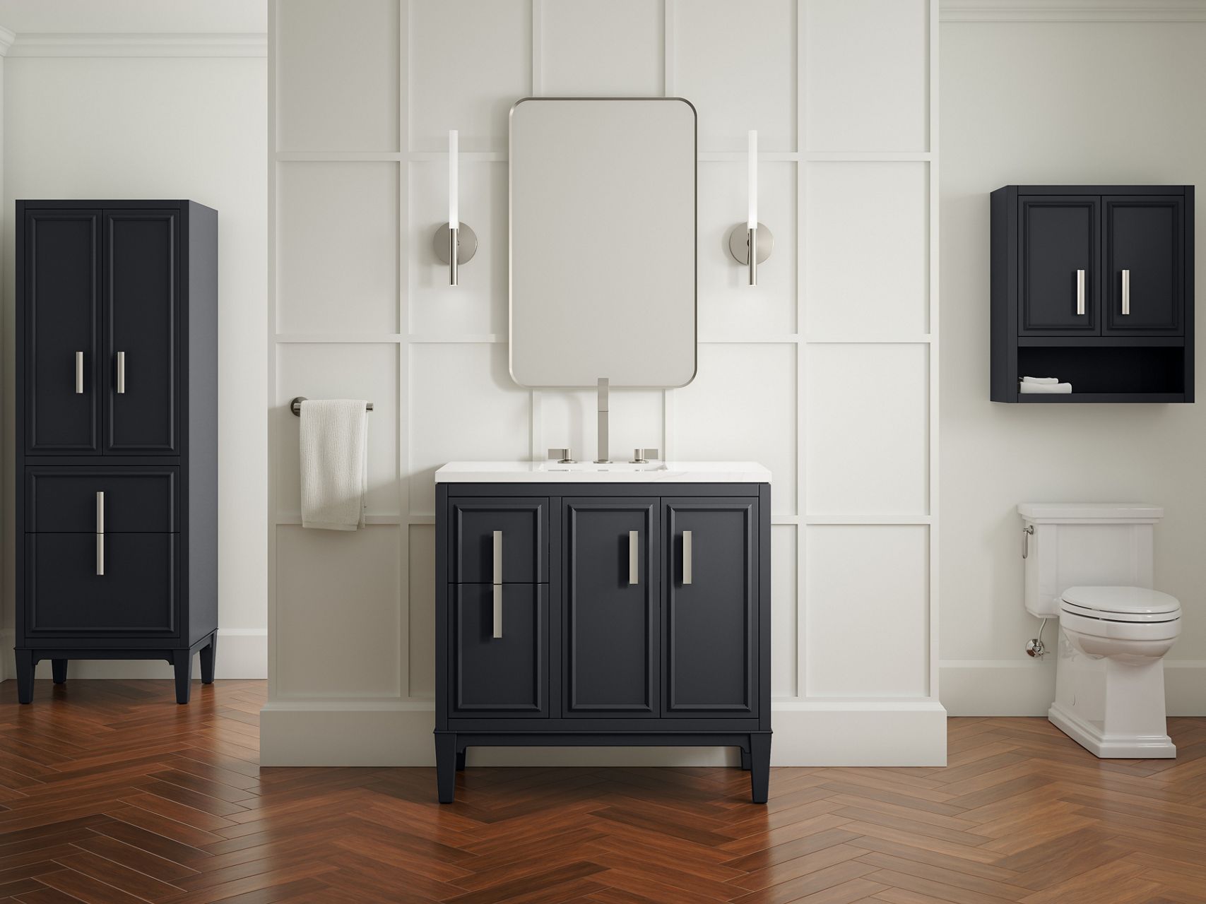 A slate grey Southerk vanity with brushed nickel hardware and faucet, a white top, and a rectangular mirror and two sconces in a bathroom with off-white walls with raised square framing.