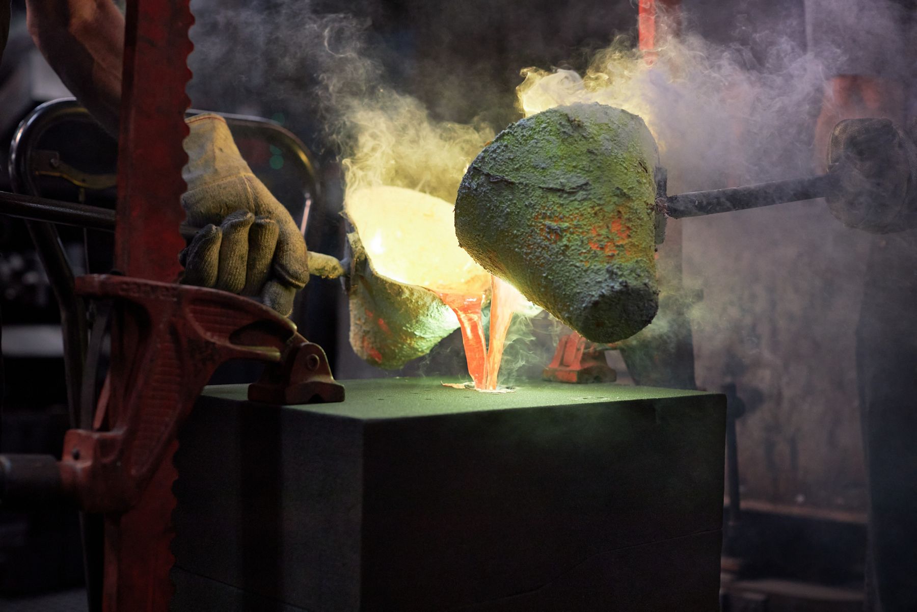 A manufacturing facility where molten metal is being poured into a mold for the brass part of the Rock.01 sink.