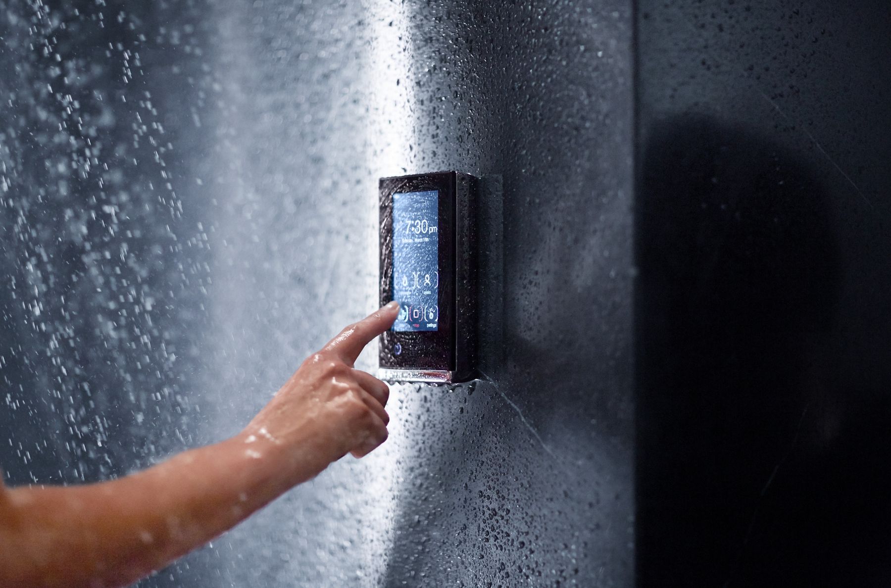 A hand using a KOHLER digital control panel to control a shower.