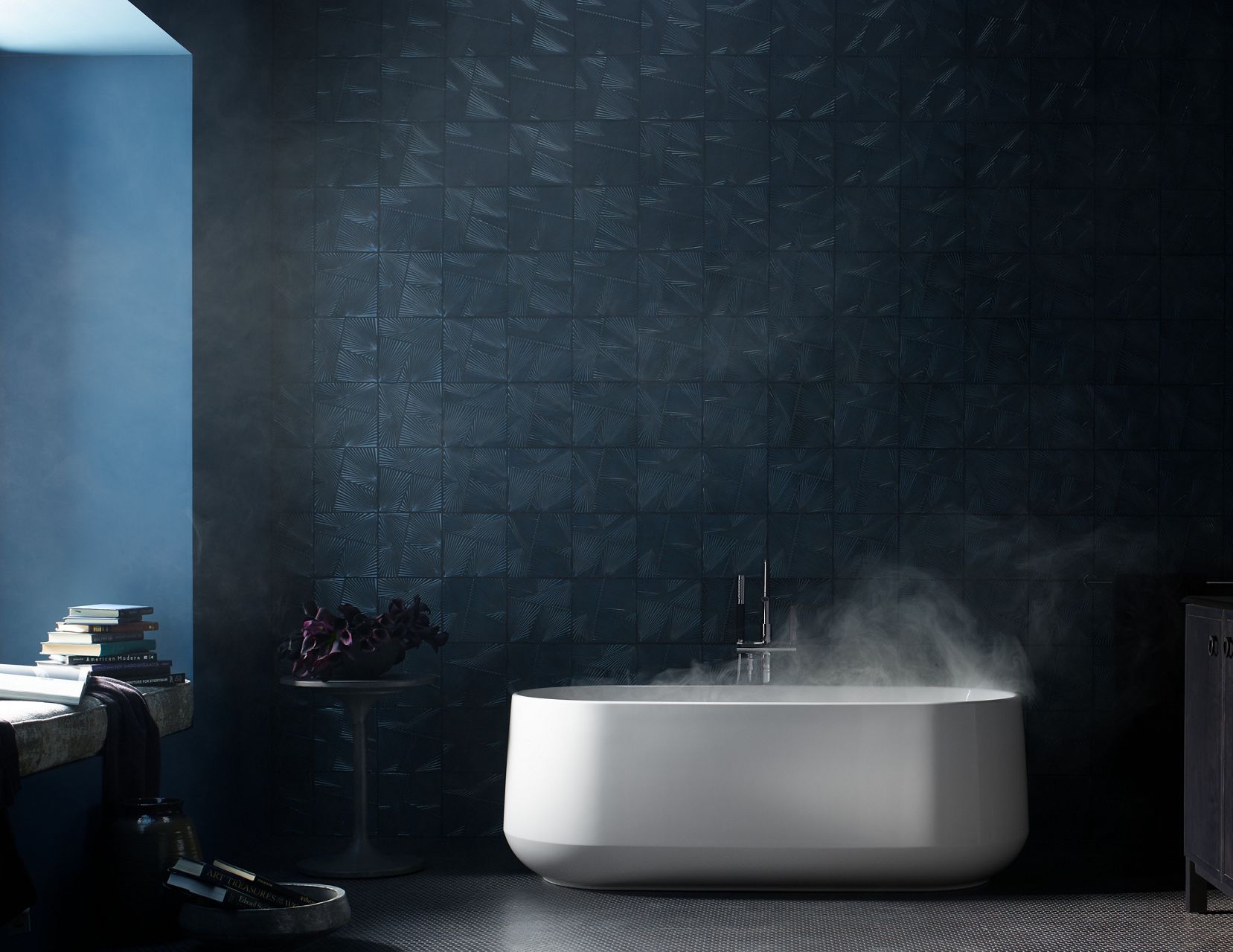 La vapeur s’élève d’une baignoire autoportante Ceric de KOHLER dans une salle de bain sombre et maussade