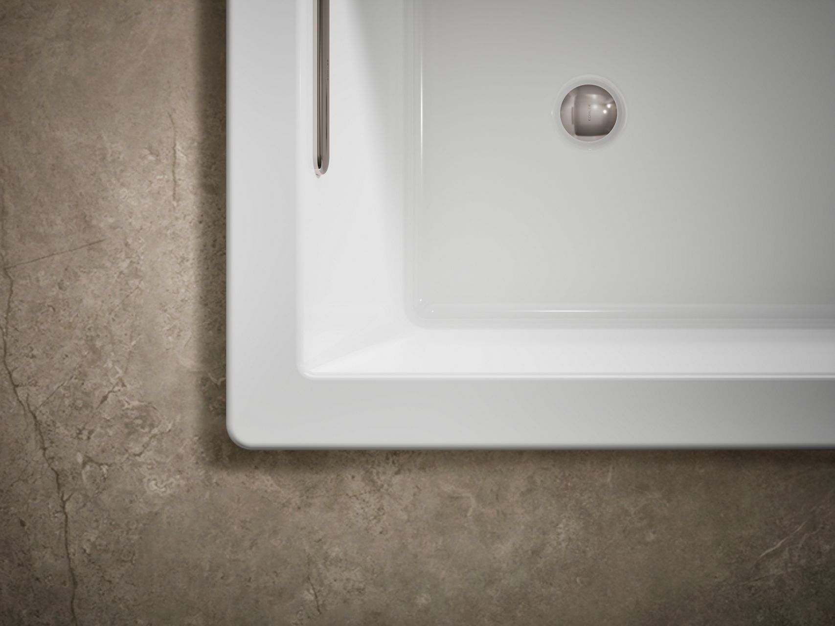 KOHLER drop-in bathtub in white acrylic set within a neutral stone deck.