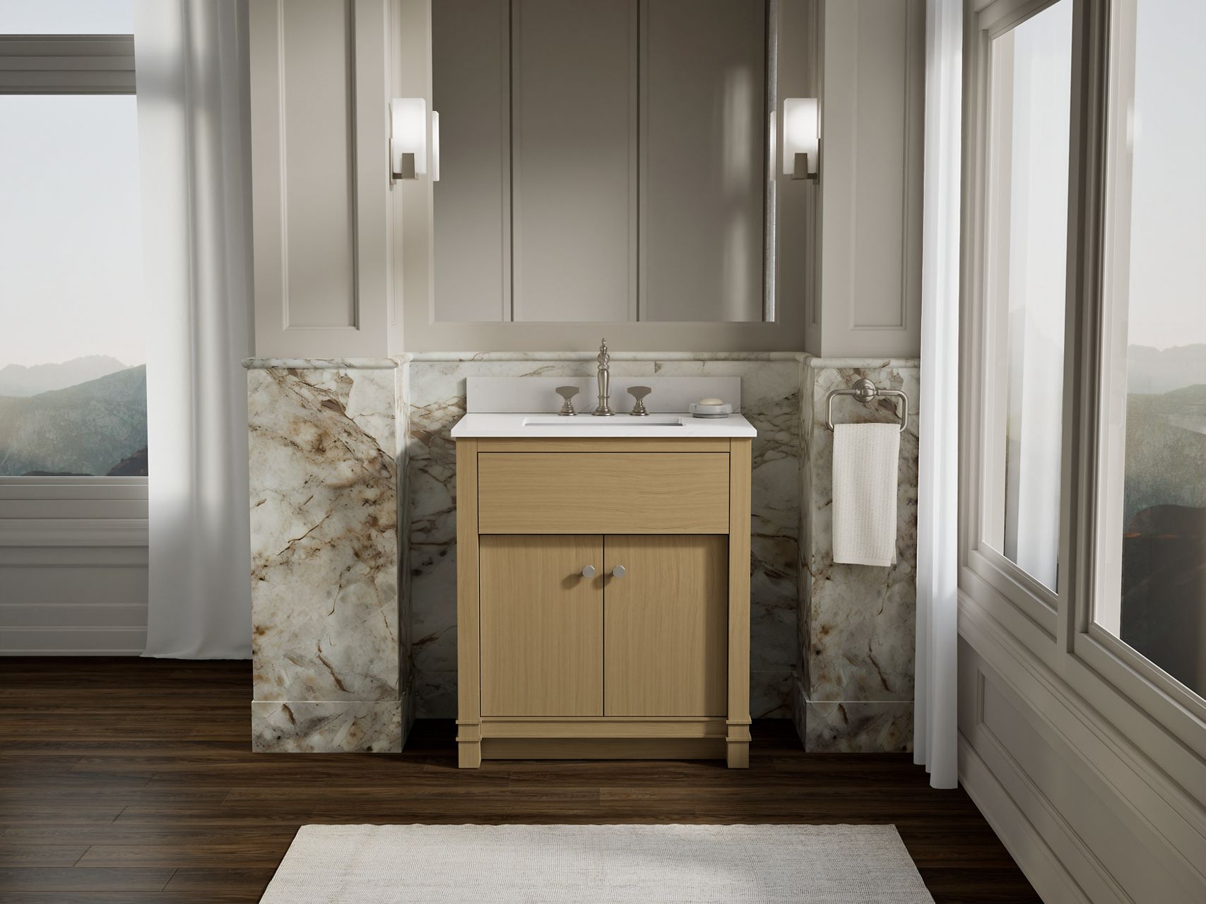 Light wood bathroom vanity with chrome faucet set against a marble backsplash in a softly lit neutral bathroom with dark wood flooring.