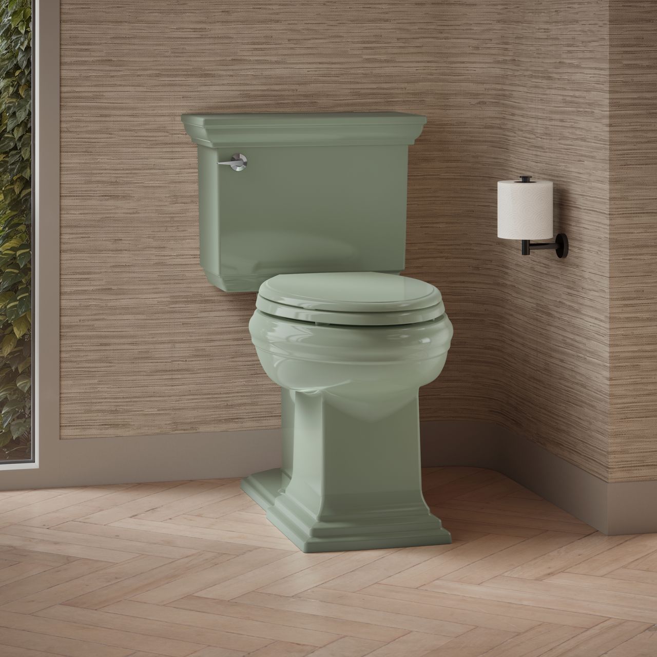 Classic two-piece toilet in a soft green color, placed against a textured beige wall with a toilet paper holder mounted on the side.
