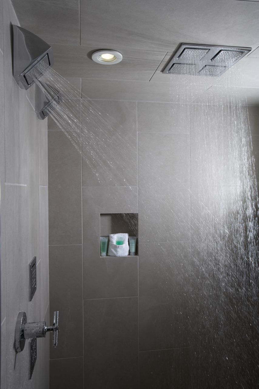 Action shot of Kohler WaterTile® body sprays in Polished Chrome showering water from top and side angles.