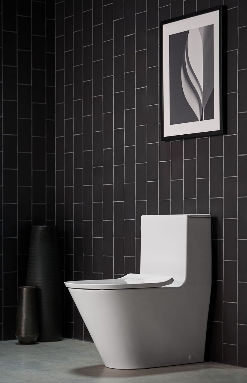 A Brazn one-piece toilet in white set against a tiled wall.