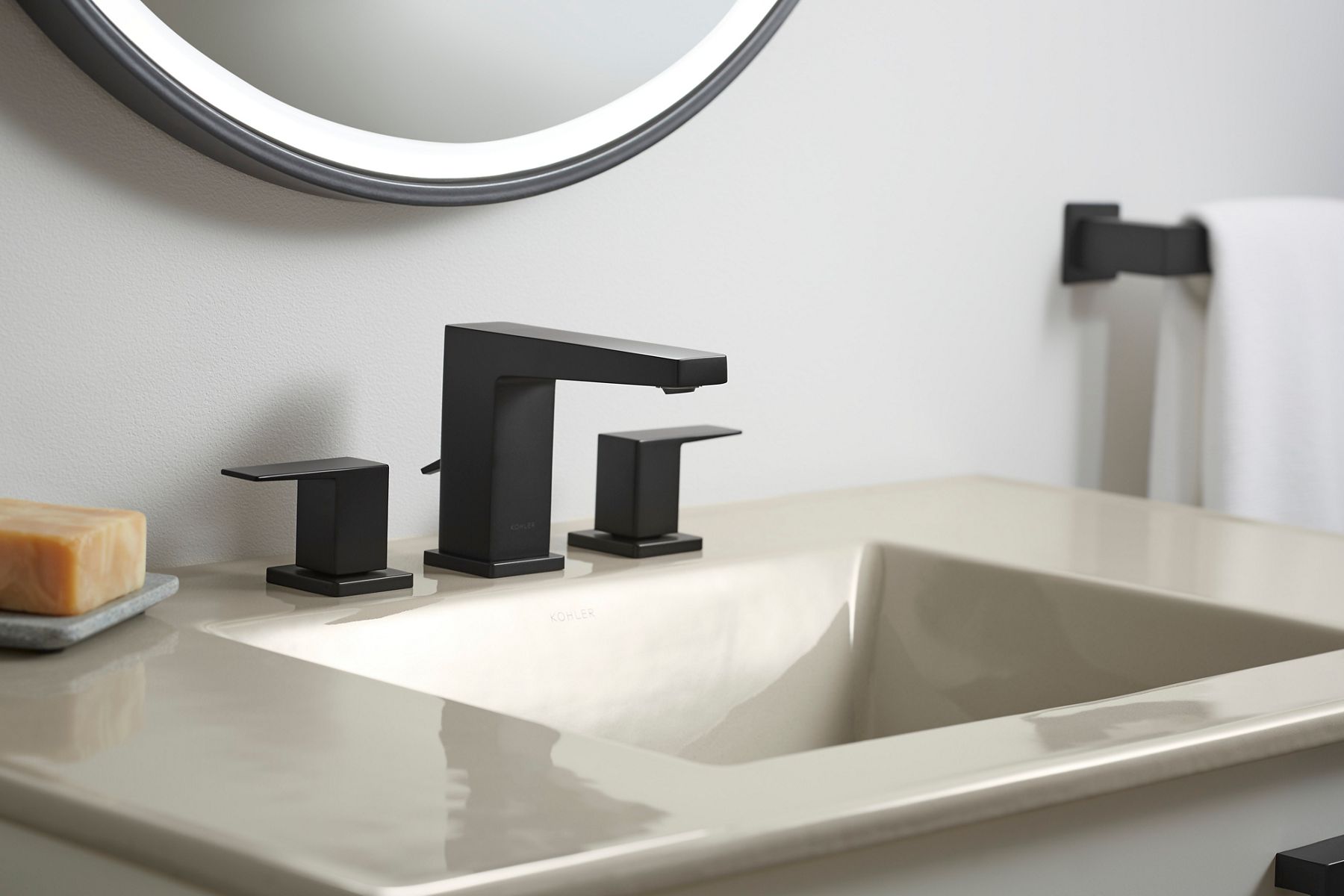 A one-piece vitreous china combination counter top and sink with a modern matte black faucet. 