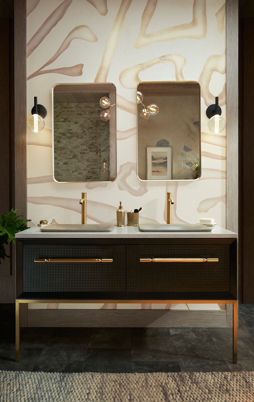 Modern bathroom design featuring double sinks with gold fixtures, large backlit mirrors, and marble wall.