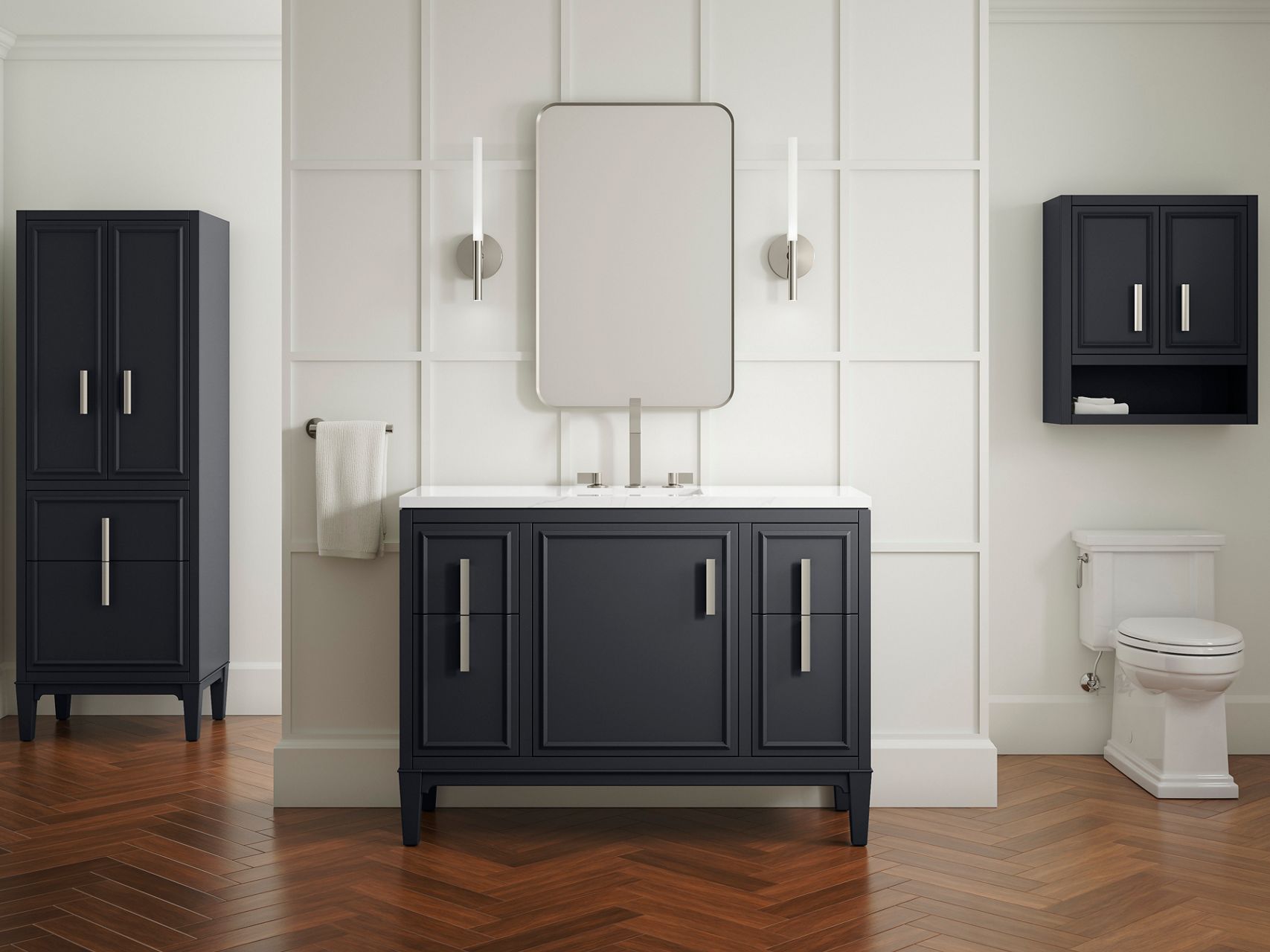 A bathroom styling space with a dark gray vanity transitional with a white counter top and brushed nickel accents against a white framed wall with a rectangular mirror and sconce lights.
