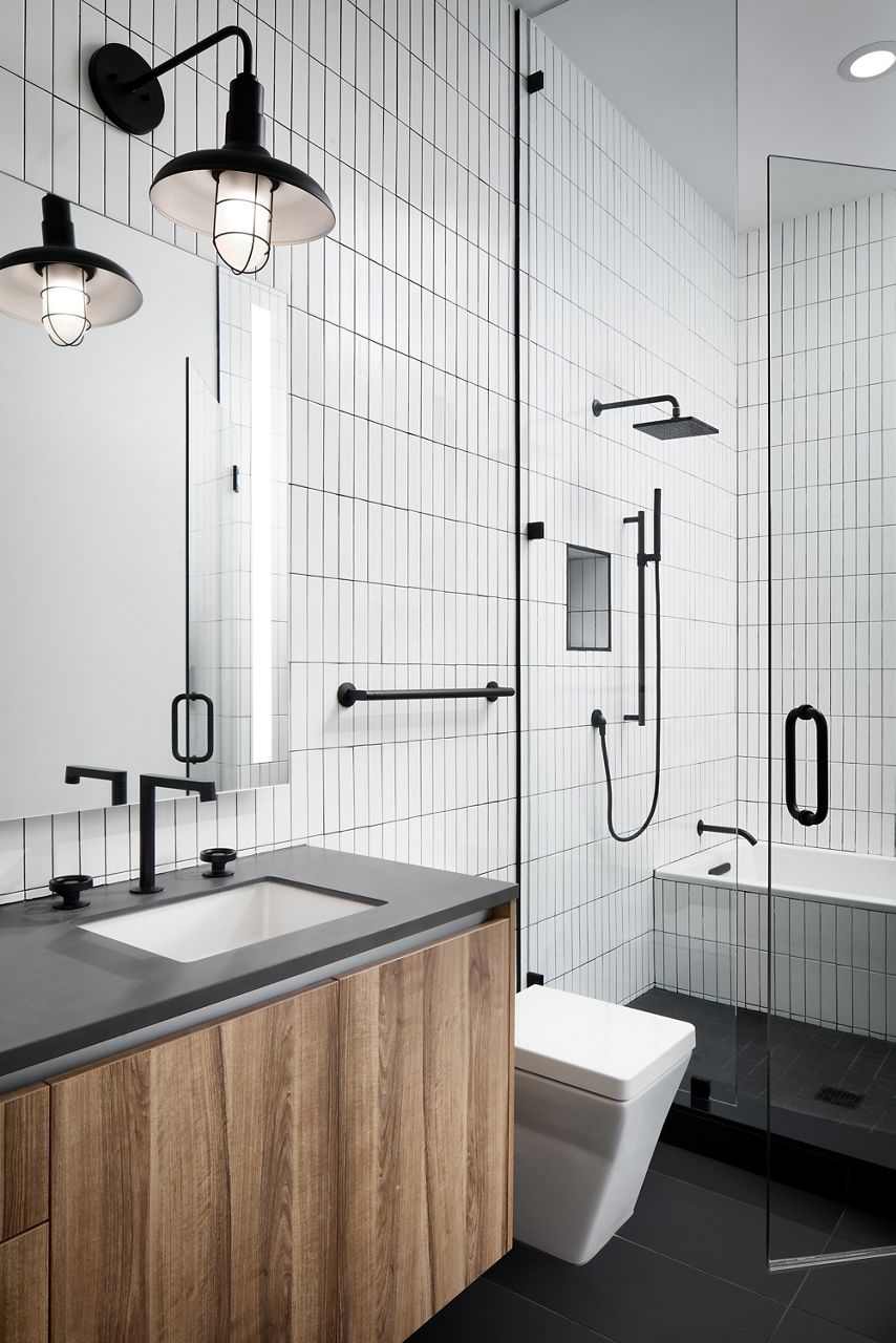 Photo of contemporary bathroom featuring white tiles and wood themed vanity with Kohler fixtures and accents in Matte Black.