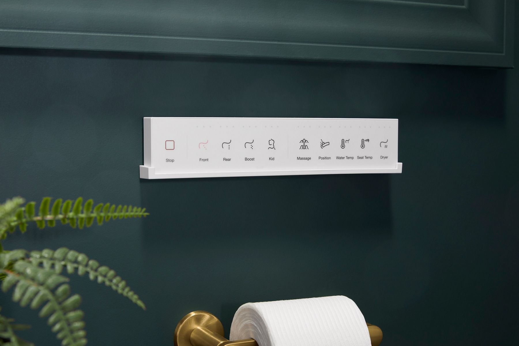 Control panel of a smart toilet with various bidet and seat settings mounted on a dark green wall above a toilet paper holder.