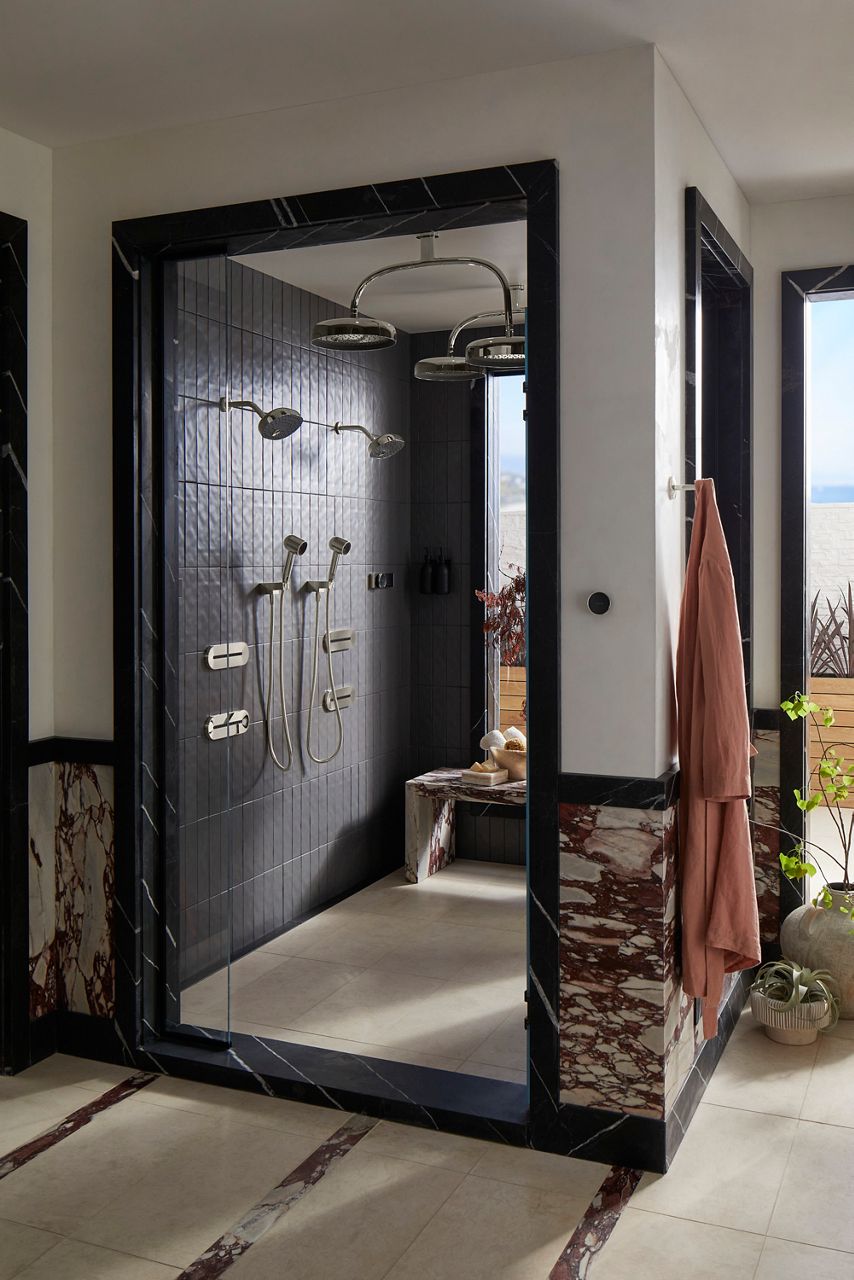 Shower space with tiled wall, two showerheads, two, hand showers, water tiles, two rain heads, digital shower control, robe hook, and decor.