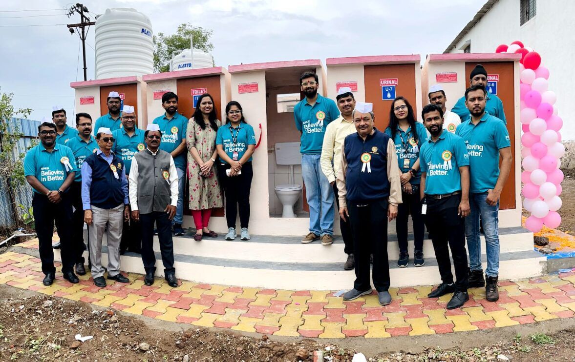 Associates in Action program team posing in front of community sanitation infrastructure.