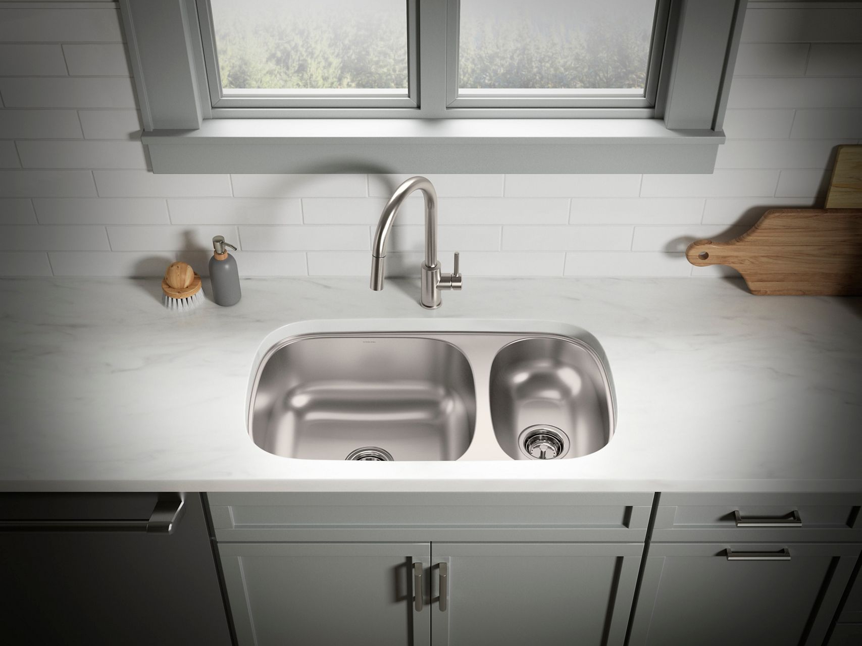 Offset double bowl stainless steel sink and faucet in a bright white and gray kitchen.