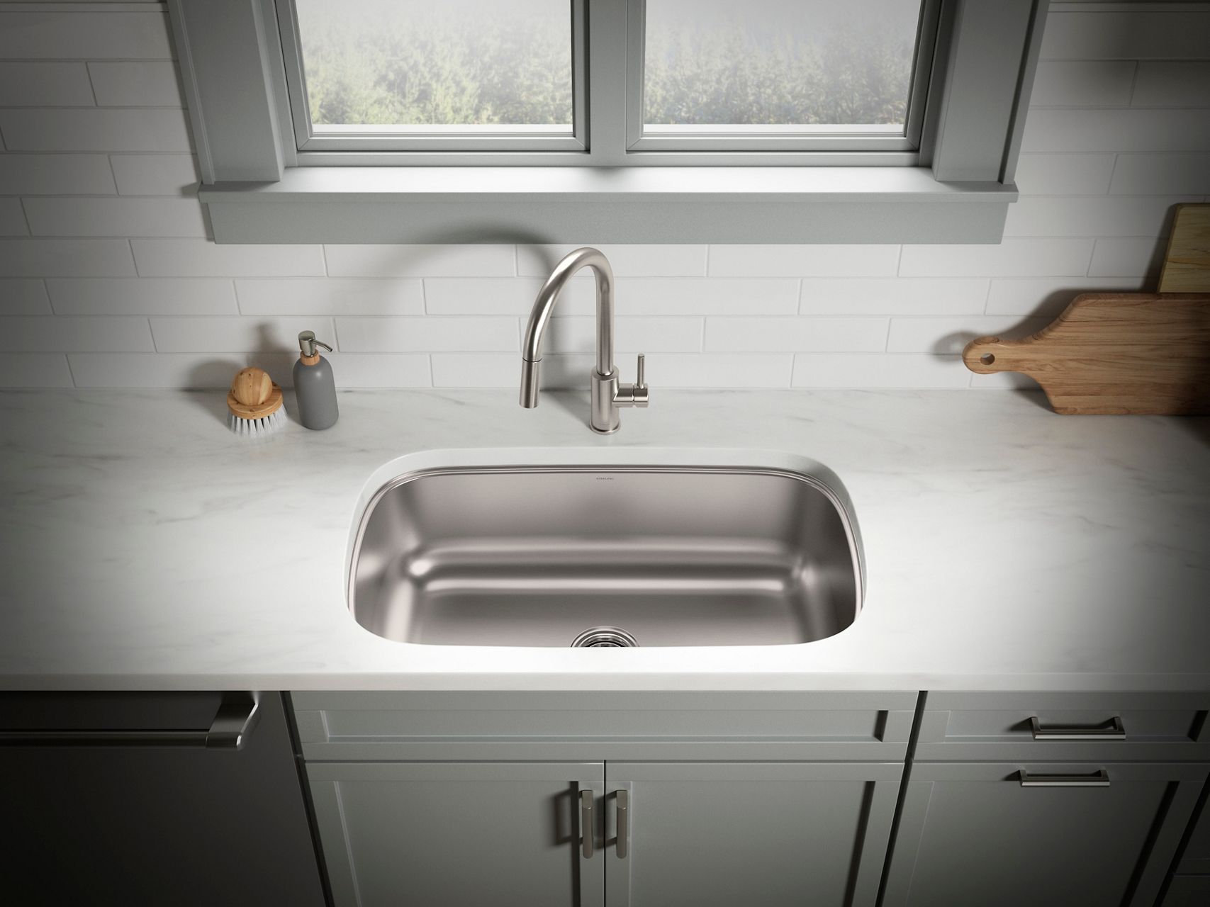 Undermount stainless steel sink and faucet in a bright white and gray kitchen.