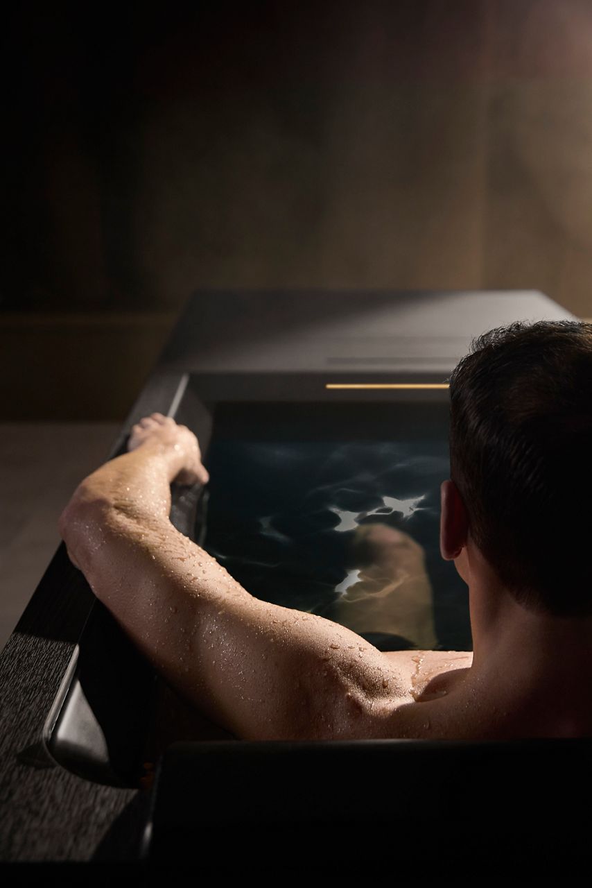 A man using a Kohler Ice Bath in a dimly lit serene room.