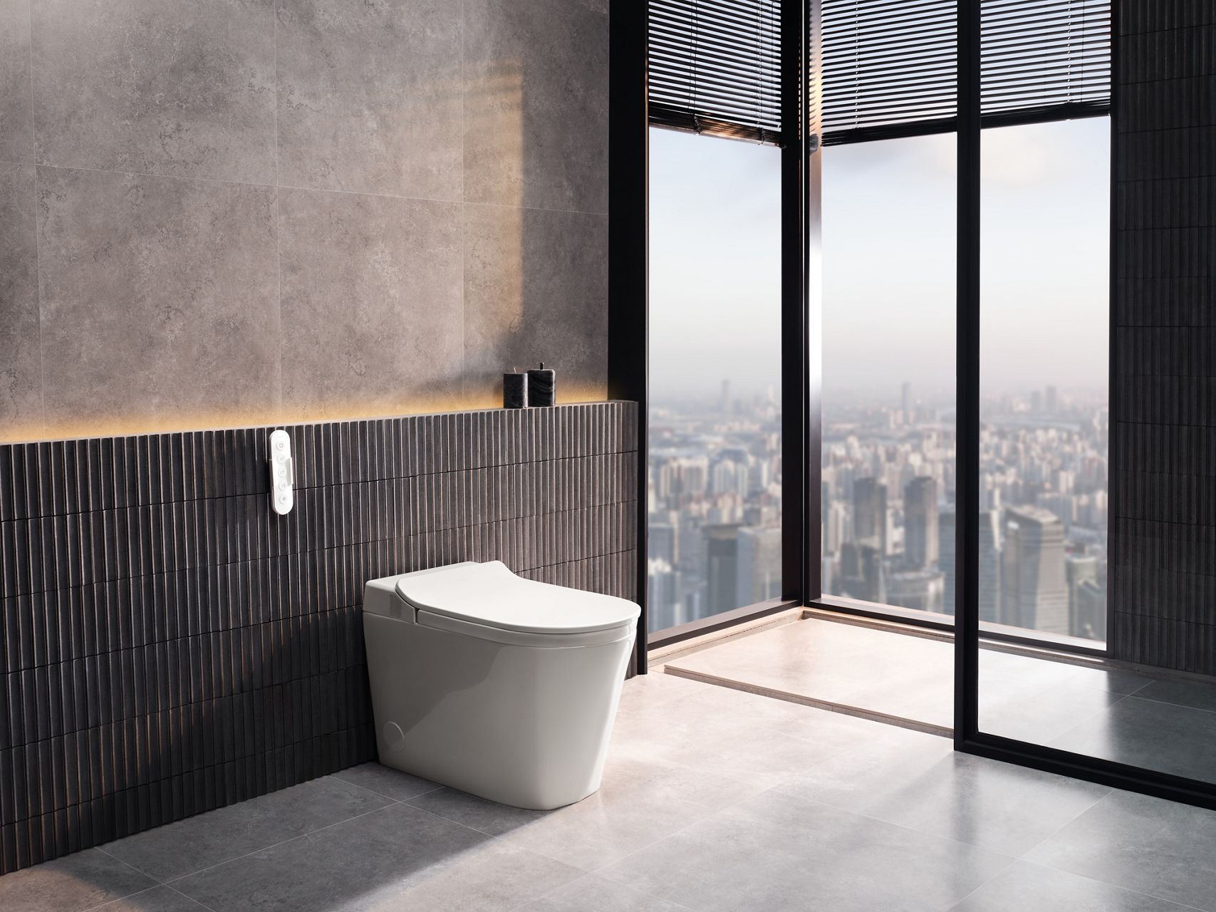 Sleek white toilet with wall-mounted remote control against dark stone tiles.