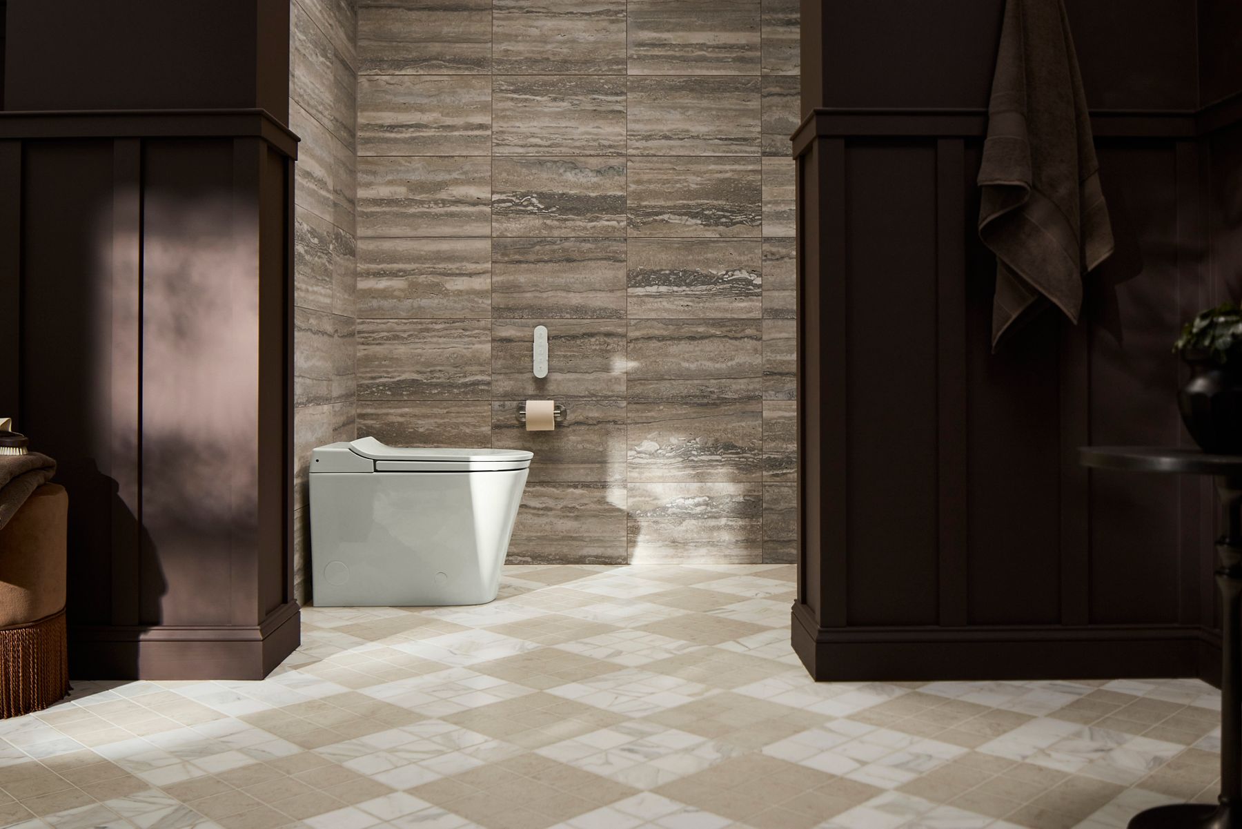 White smart toilet in a sunny bathroom with gray stone walls and cream tiled flooring.