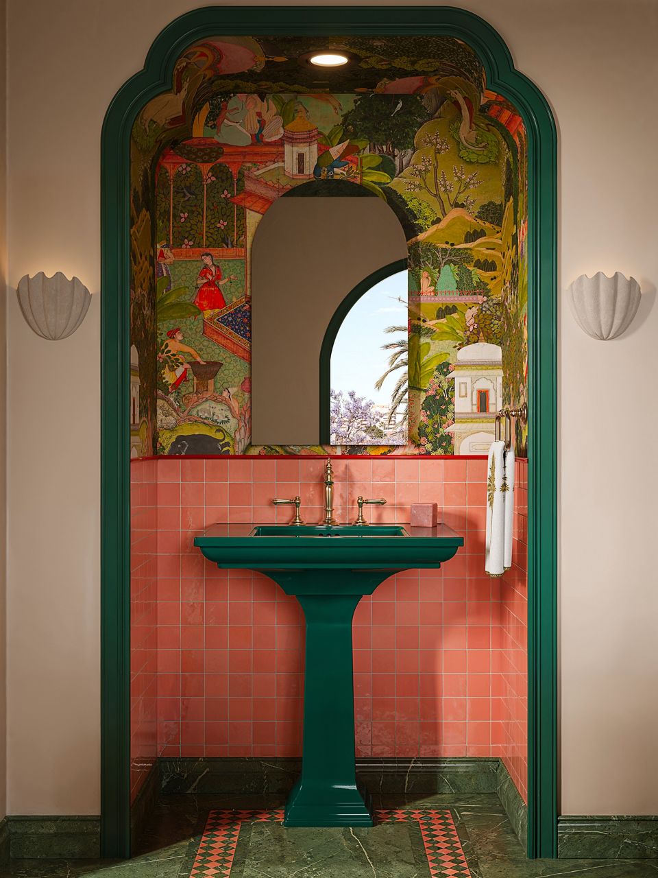 A bold statement bathroom featuring a vibrant green toilet, arched doorway, and elaborate pink and green tiling.