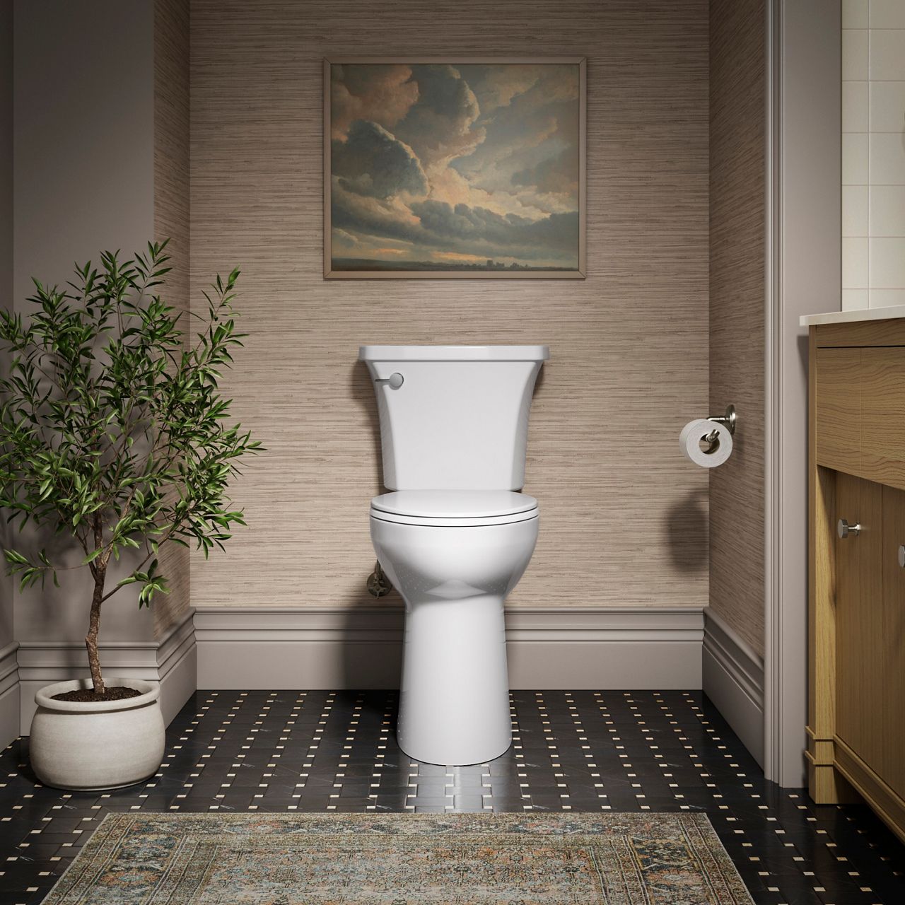 Bathroom interior featuring a white KOHLER toilet centered against a textured wall, with dark tile flooring, framed landscape artwork, a potted plant, and a wood vanity partially visible on the right.