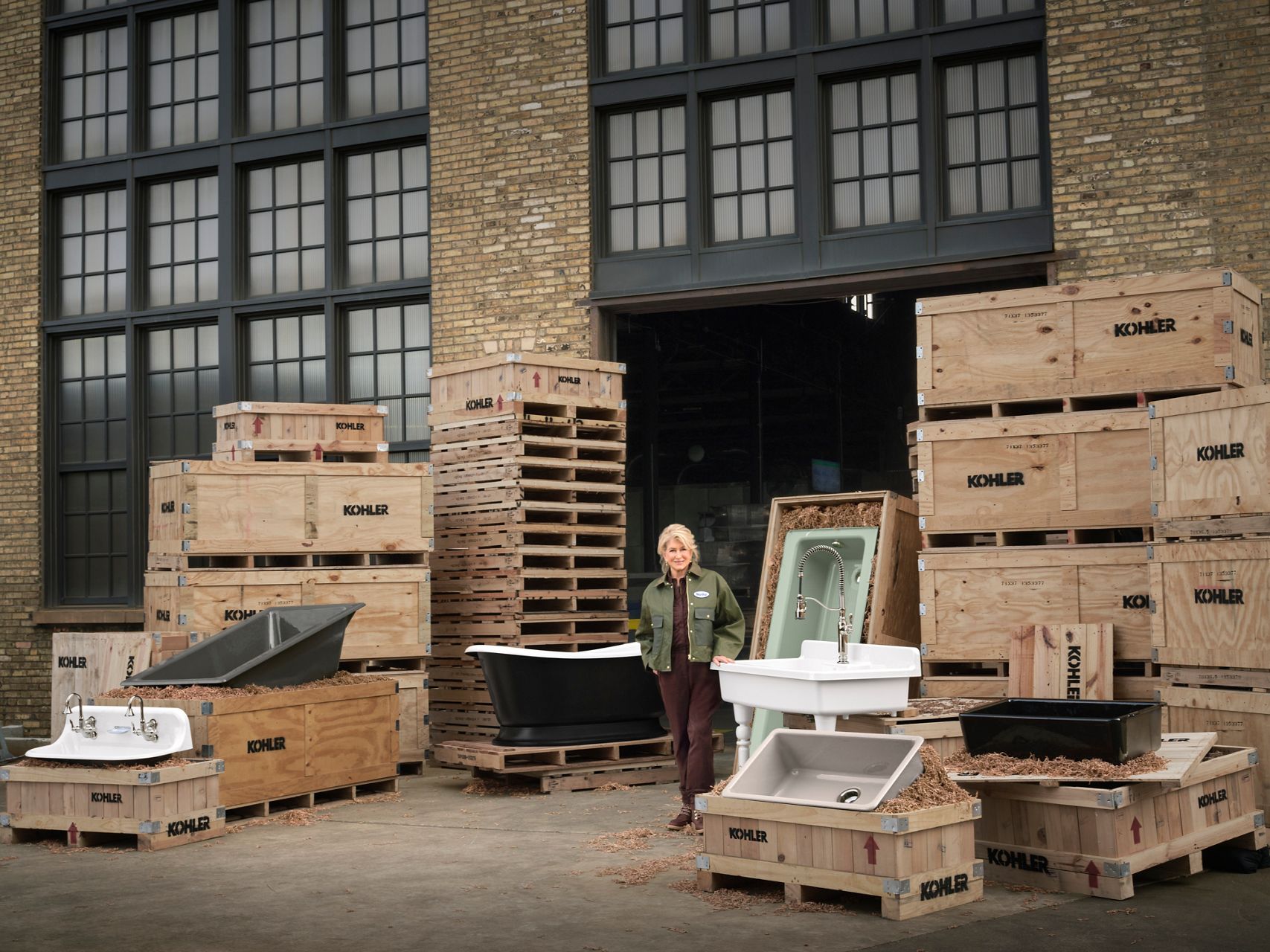 Martha Stewart standing outside alongside enameled cast iron bathtubs and sinks.