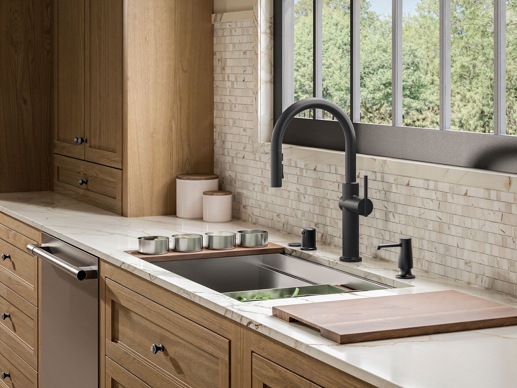 KOHLER kitchen sink with stainless steel accessories and a matte black faucet and soap dispenser.