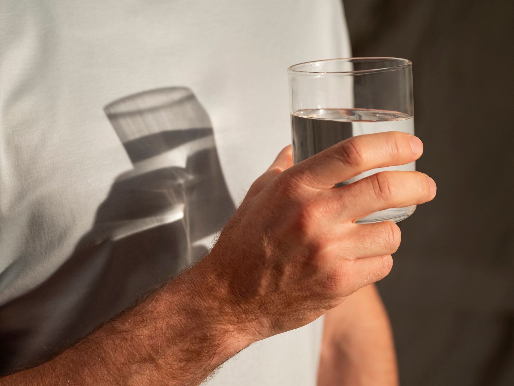 Close-up of a person holding a glass of water, representing hydration tracking and wellness insights from the Kohler Health app.