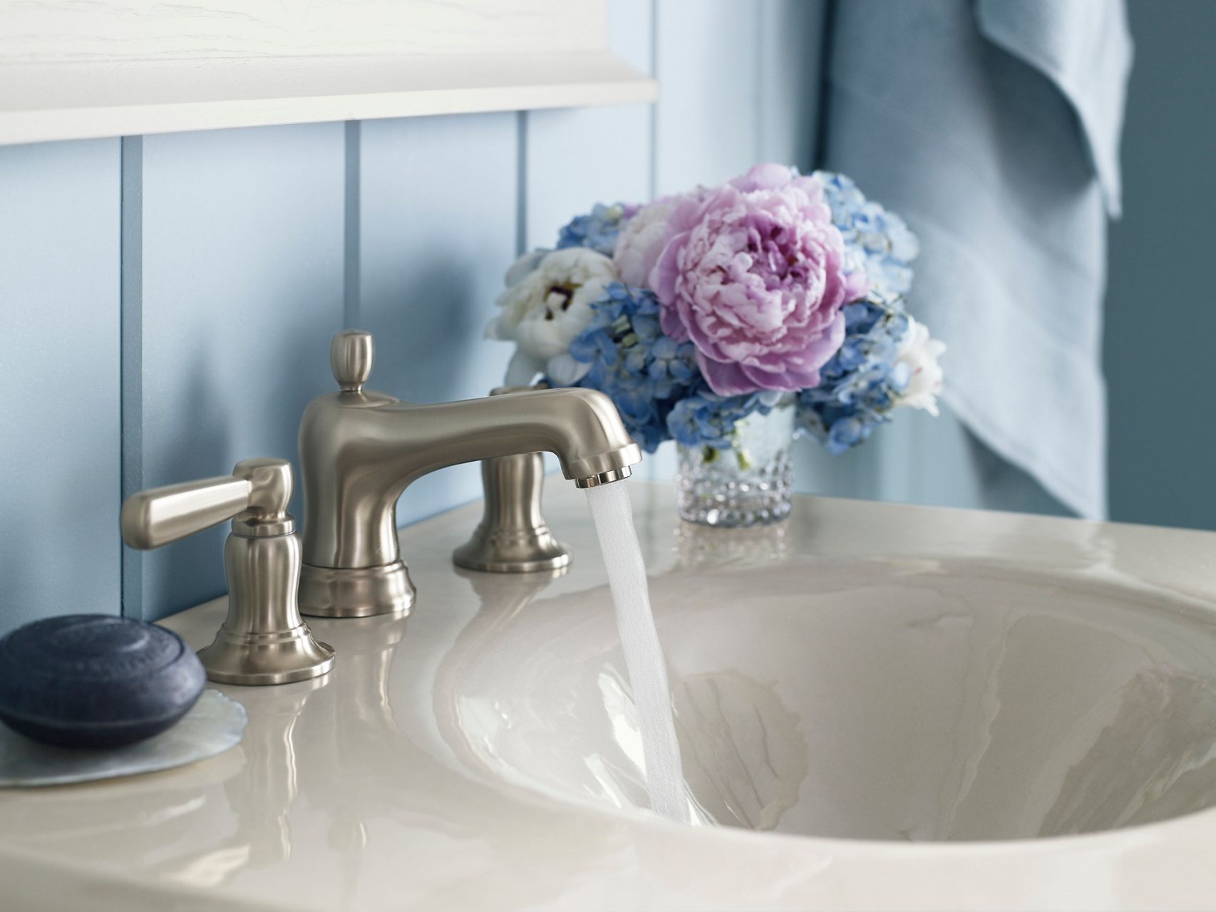 Close-up detail of a brushed nickel faucet on a single piece cast iron countertop and sink in a light beige color.