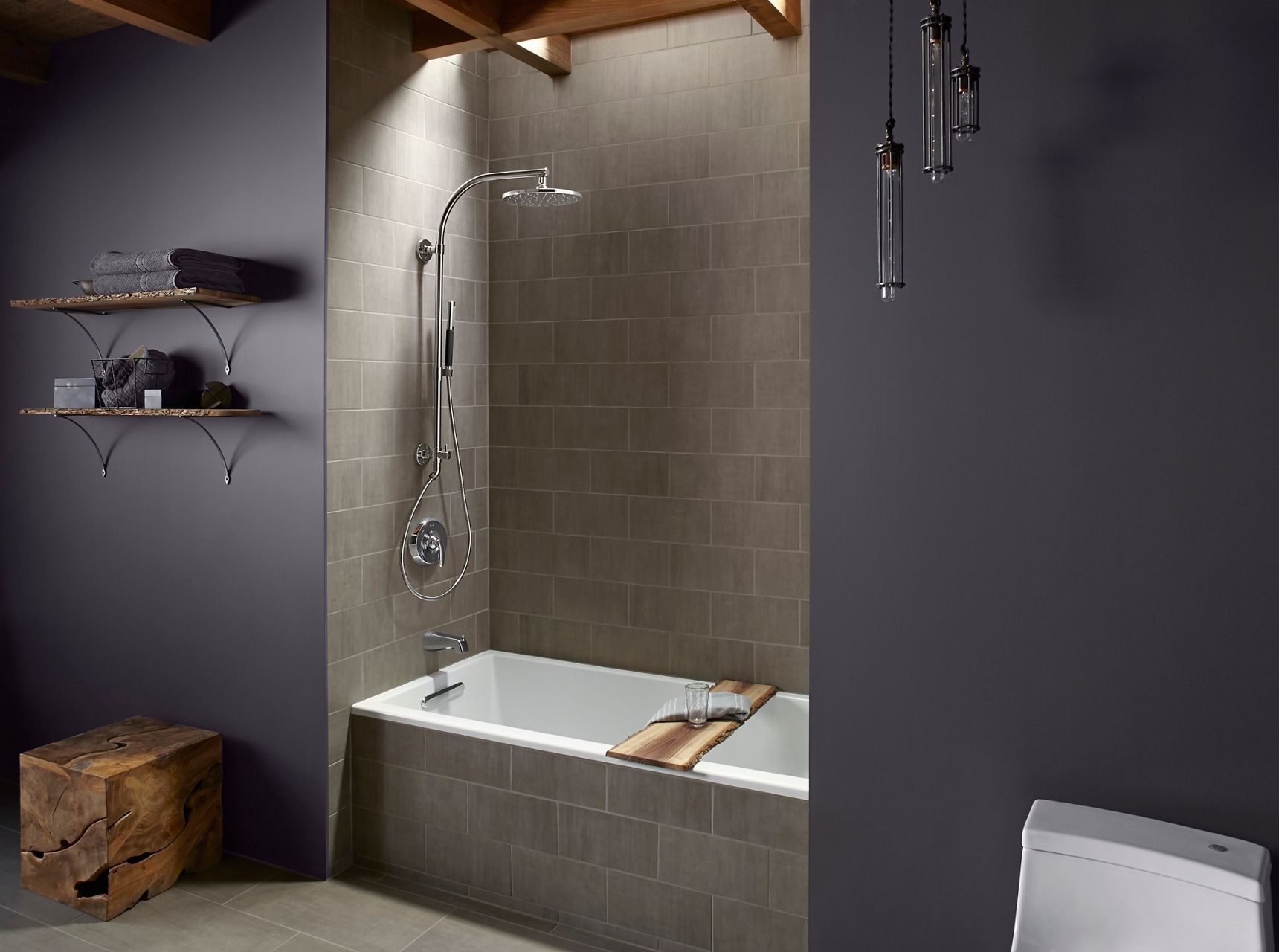 Une douche carrelée avec colonne de douche HydroRail de KOHLER et pomme de douche à effet de pluie.