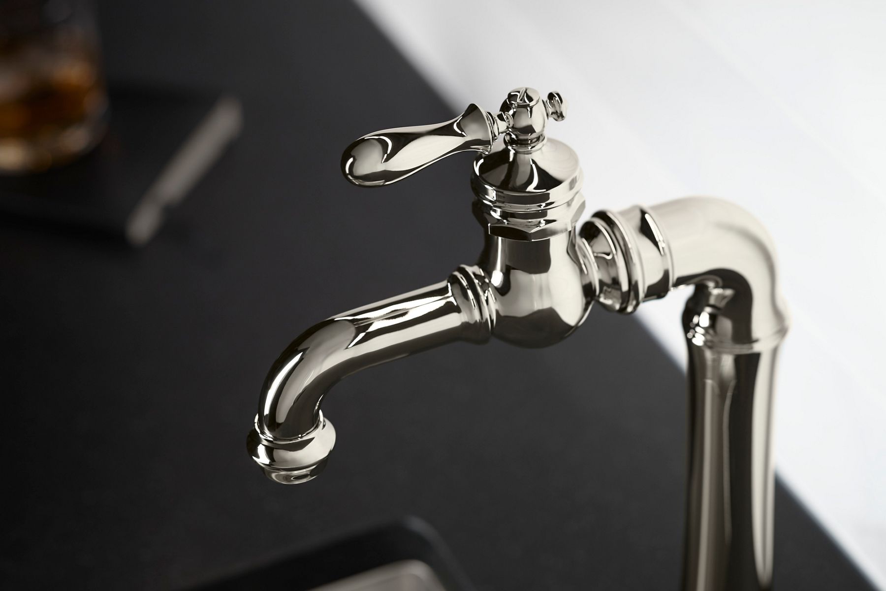 Close-up of a polished chrome bathroom faucet with a traditional lever handle on a dark countertop.