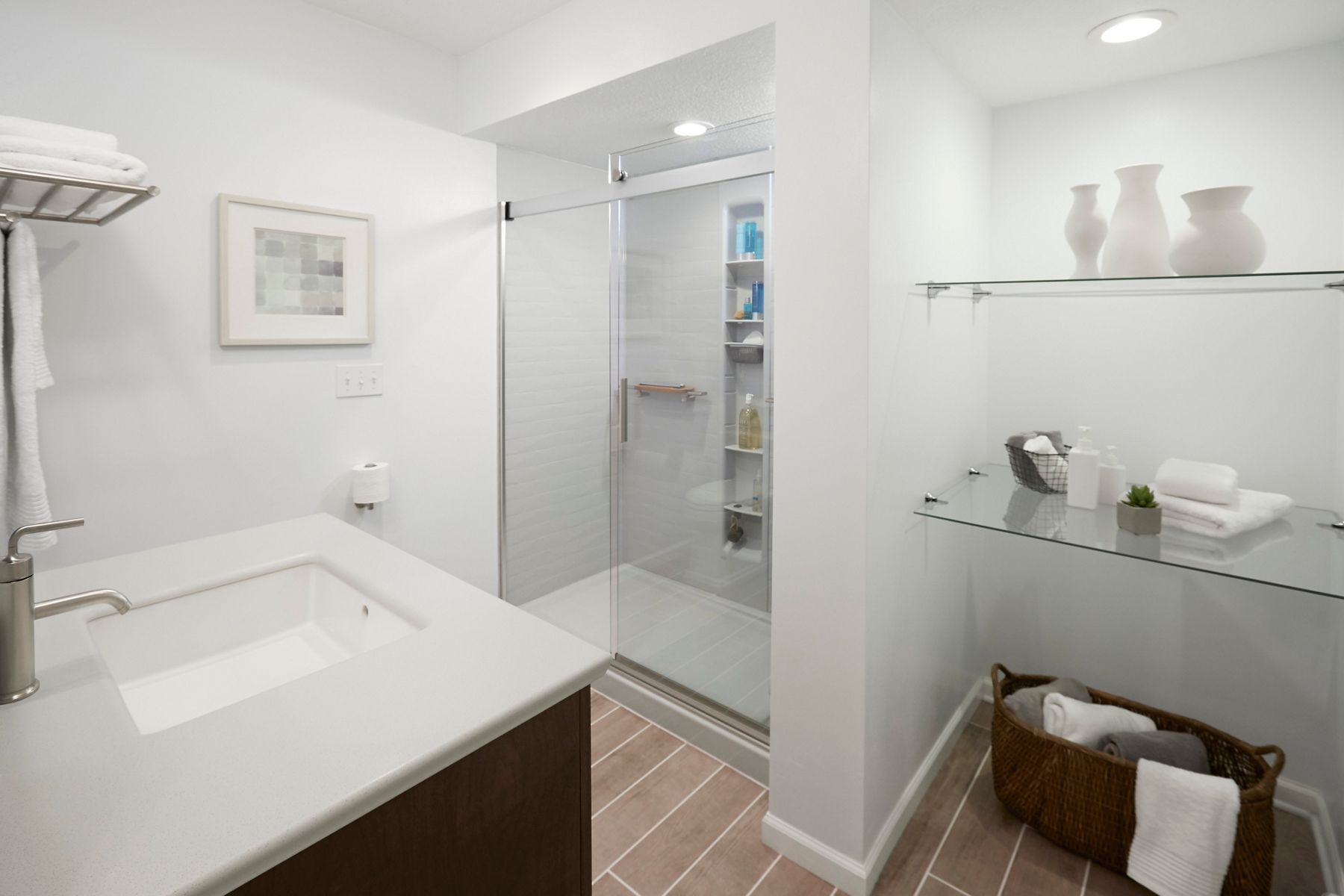Après rénovation, la salle de bain dispose d’une grande douche de plain-pied au lieu d’une baignoire, d’un meuble-lavabo modernisé et d’un espace de rangement supplémentaire