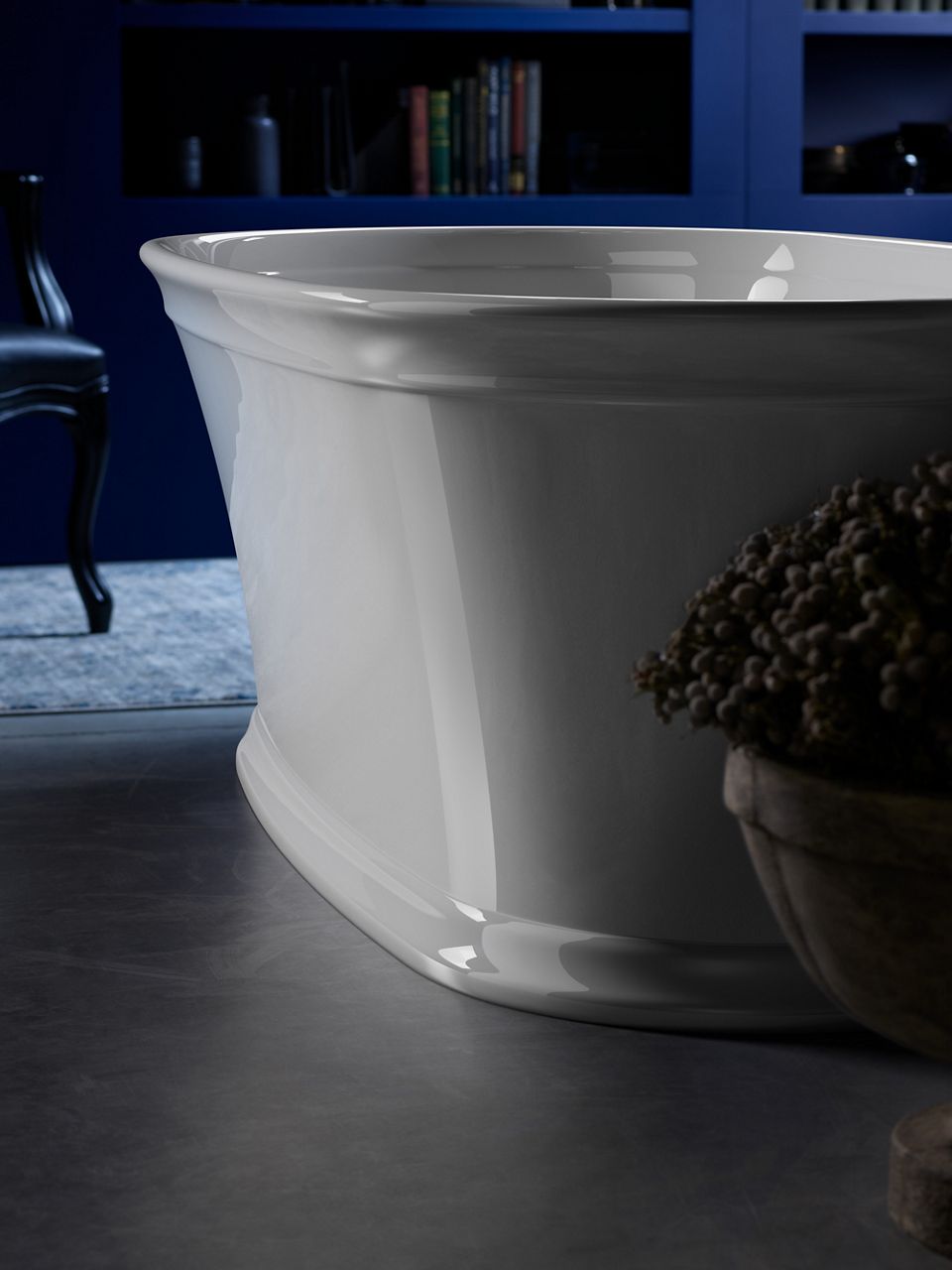 A white Memoirs freestanding bath in a dark room with a bluish light in the background.