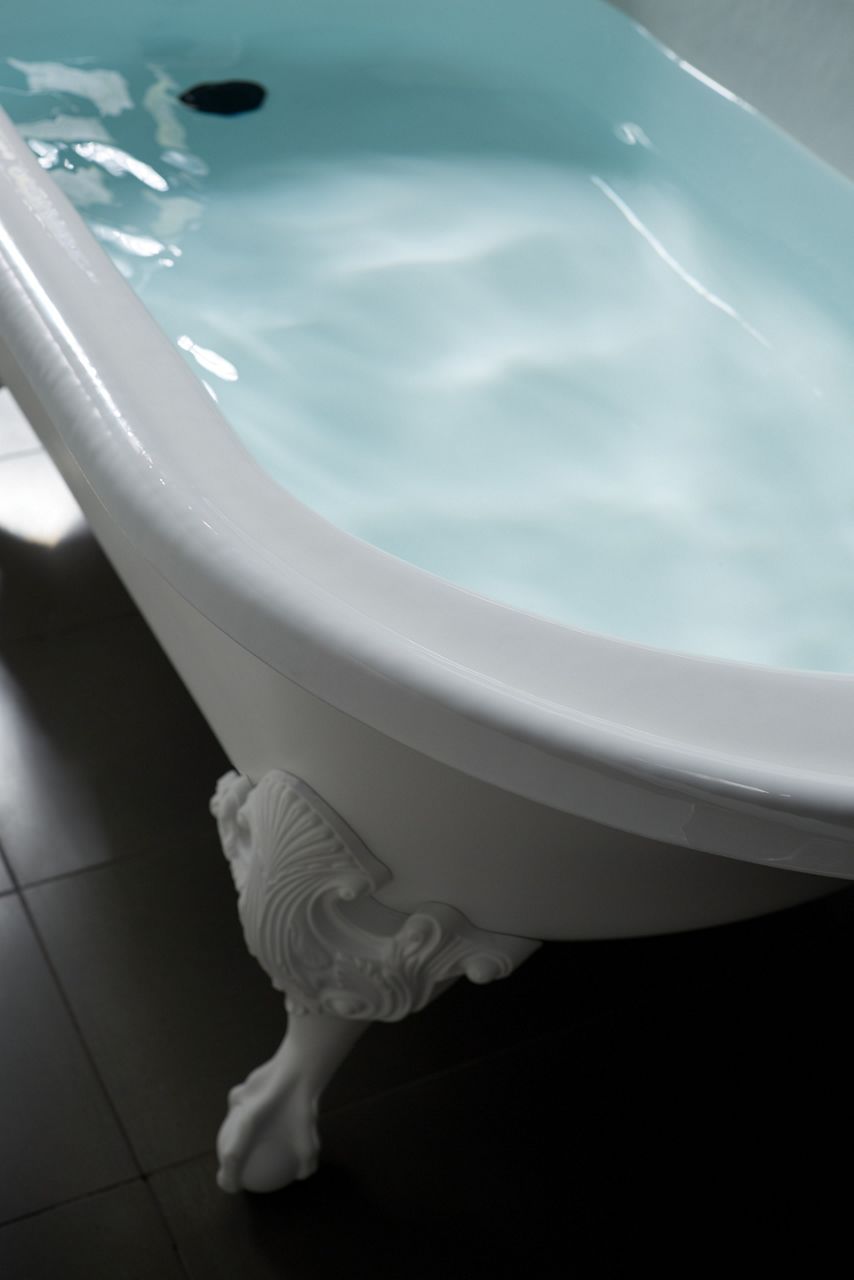 Detail of an enameled cast iron bath filled with water.