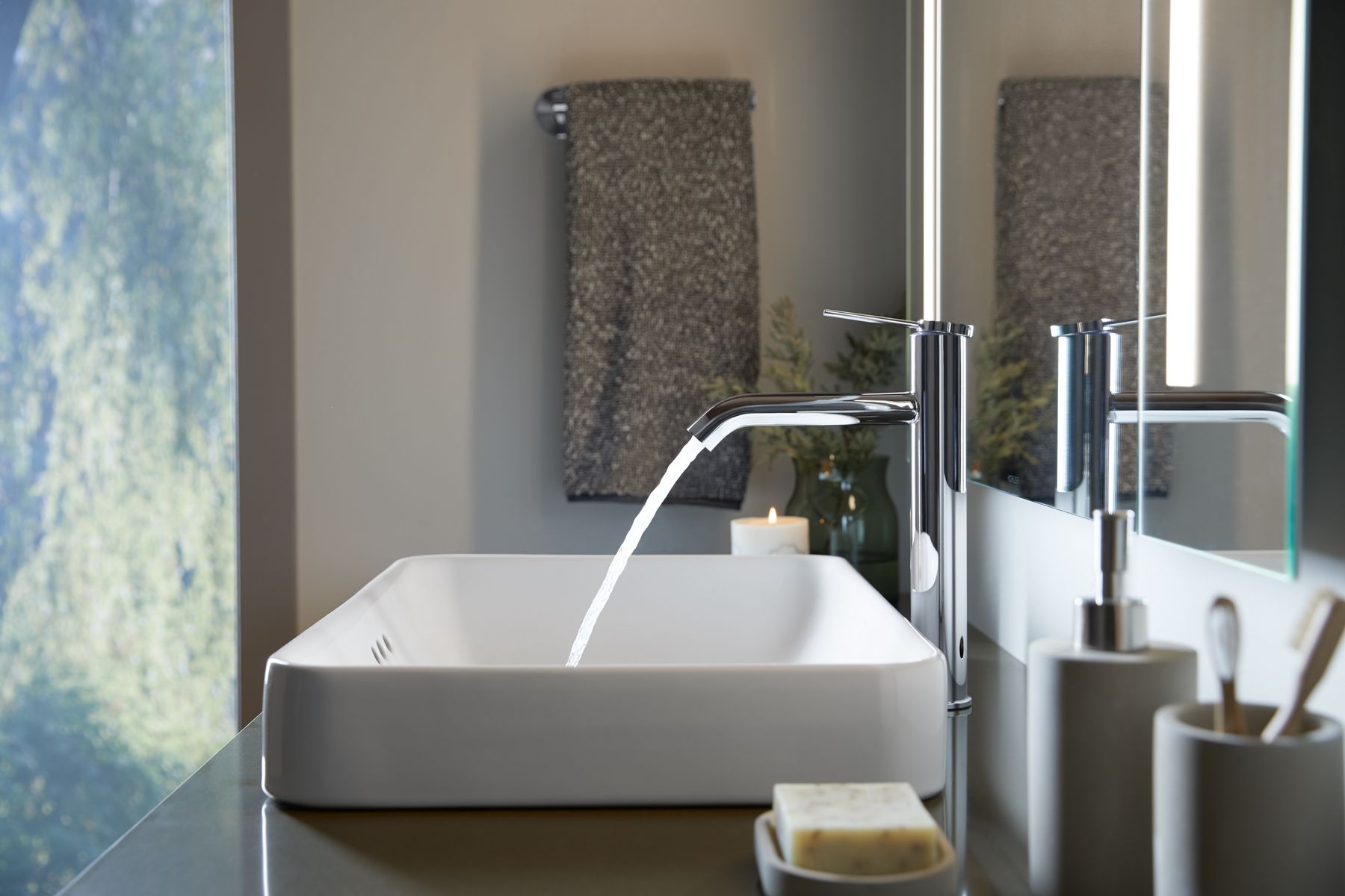 Contemporary chrome bathroom faucet with a tall, sleek silhouette on a white sink.