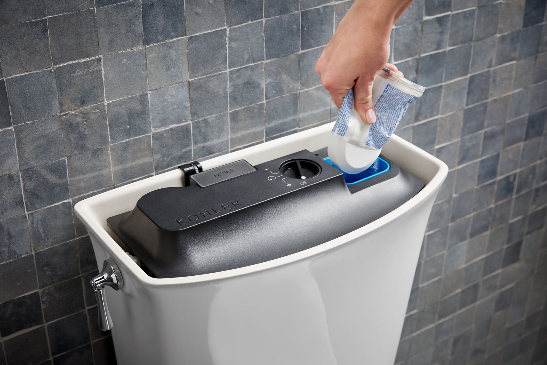 A person adds cleanser to a KOHLER ContinuousClean system installed in a white toilet tank.