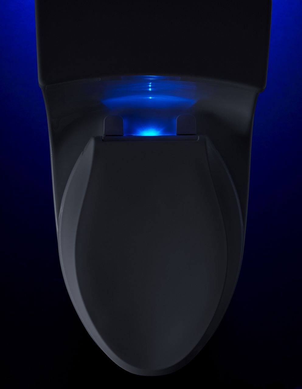 A white toilet equipped with a lighted toilet seat glows blue in the dark.