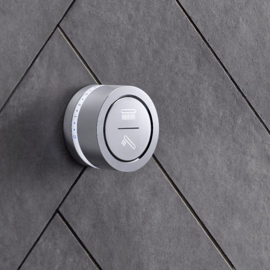 Close-up of KOHLER DTV mode shower interface in polished chrome installed on a gray stone tiled shower wall.