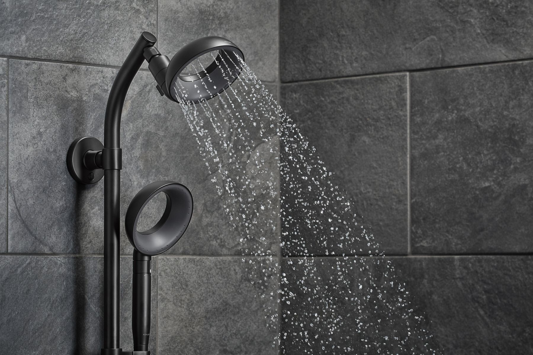 Modern black rainfall showerhead with water running.