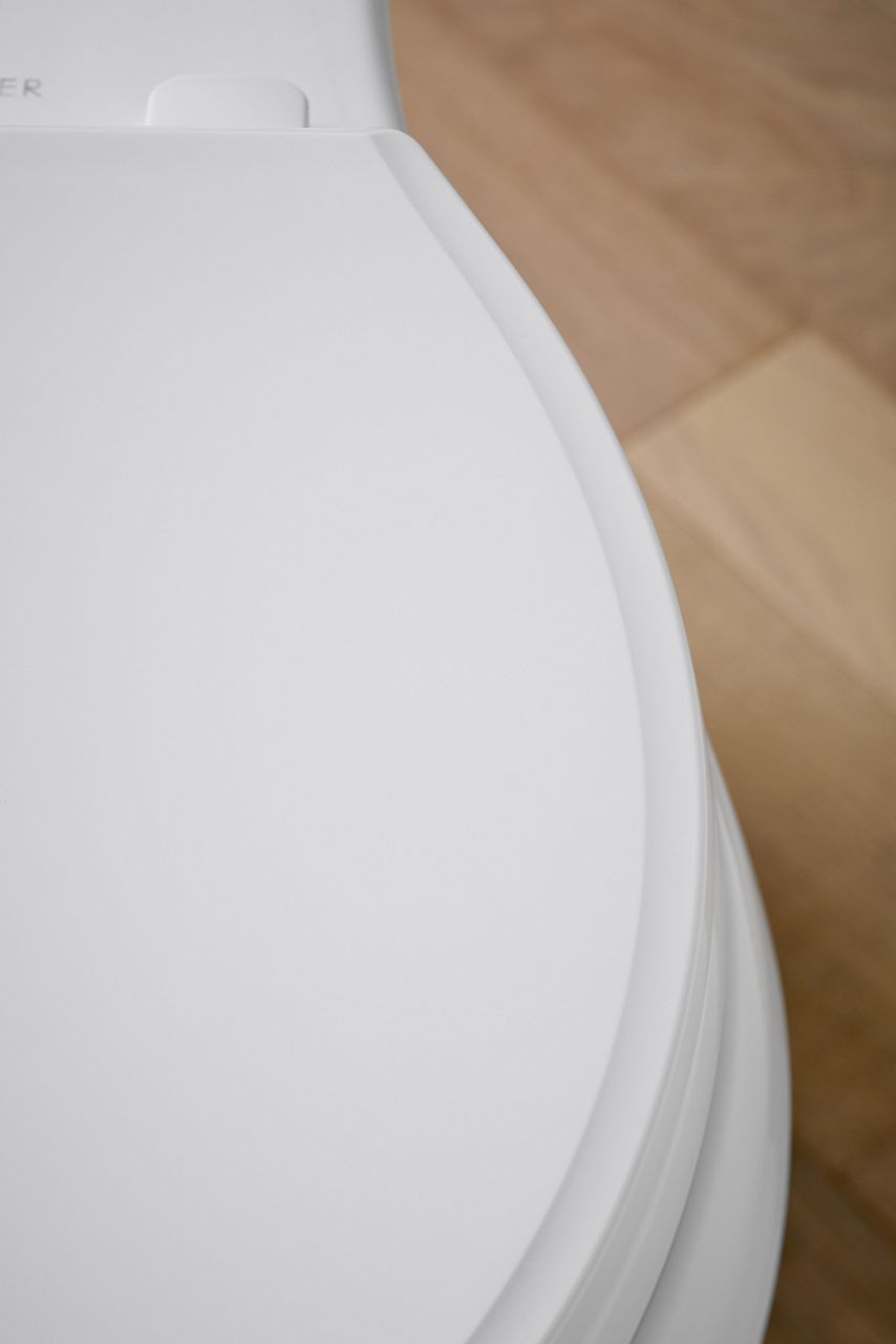 A side view of a closed white toilet seat.