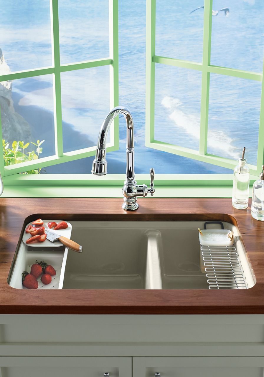 A detail view of a wooden counter with white KOHLER divided undermount sink with integrated work area and drainage rack.