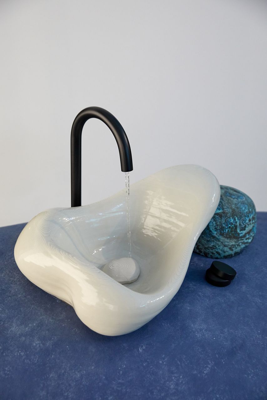 A Rock.01 sink and matte black faucet sitting on top of a large violet stone-like sculpture.