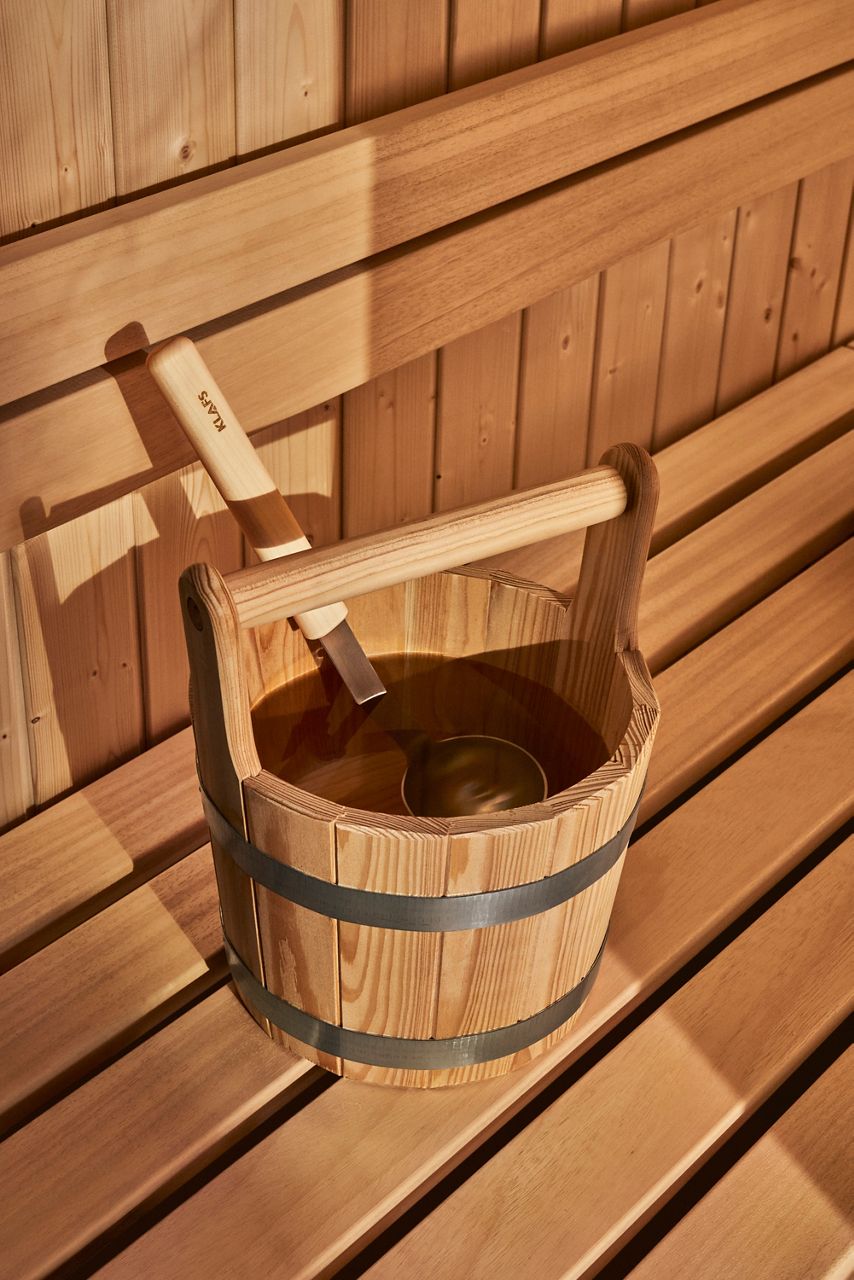 Wooden sauna bucket and ladle resting on a traditional sauna bench
