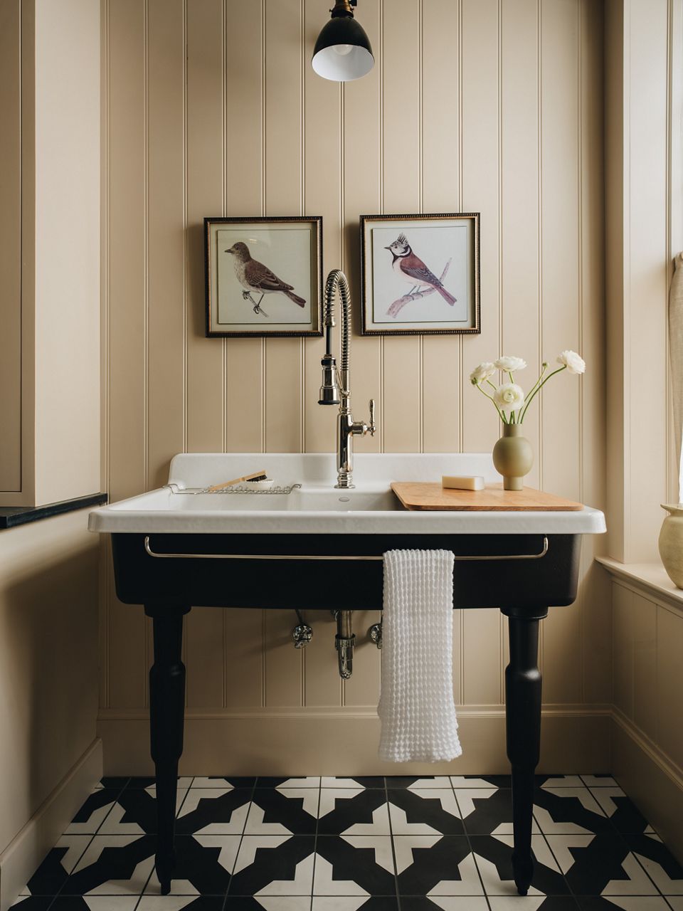 A laundry room with a large wall mount farmhouse sink on legs that includes a large pull down faucet.