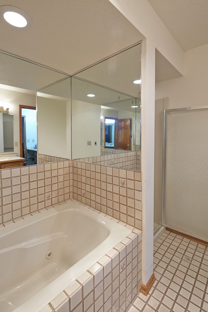 Une vue sur l’ancienne baignoire avec un petit contour carré de carreaux et des murs
