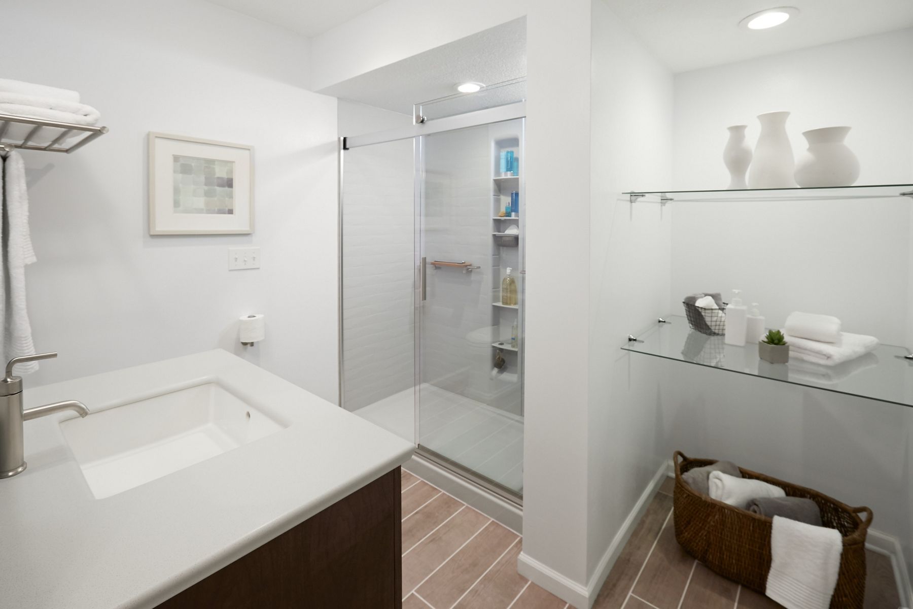 Après rénovation, la salle de bain dispose d’une grande douche de plain-pied au lieu d’une baignoire, d’un meuble-lavabo modernisé et d’un espace de rangement supplémentaire