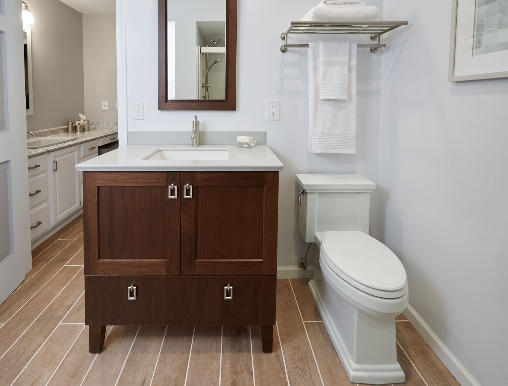 Une salle de bain modernisée avec des planchers en carrelage de grand format, une nouvelle toilette monopièce Kohler et un meuble-lavabo, un lavabo et un robinet élégants et nouveaux.