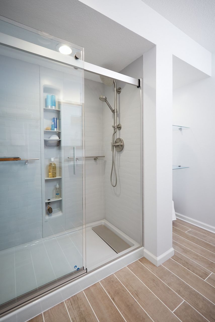 Après la rénovation, la salle de bain dispose d’une spacieuse douche de plain-pied avec colonne de douche Kohler, douchette et rangement