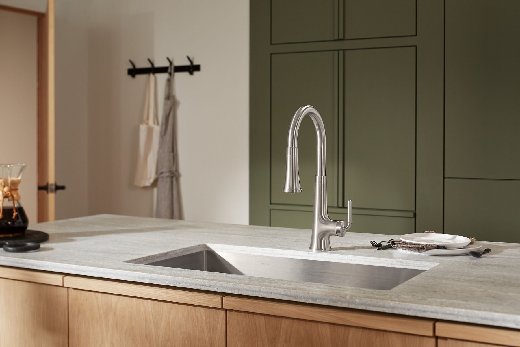 A kitchen island with white top, undermounted sink, and KOHLER single lever handle pullout faucet.
